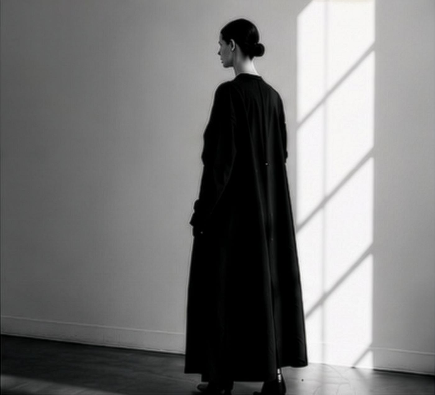 Model in a long black coat by a window